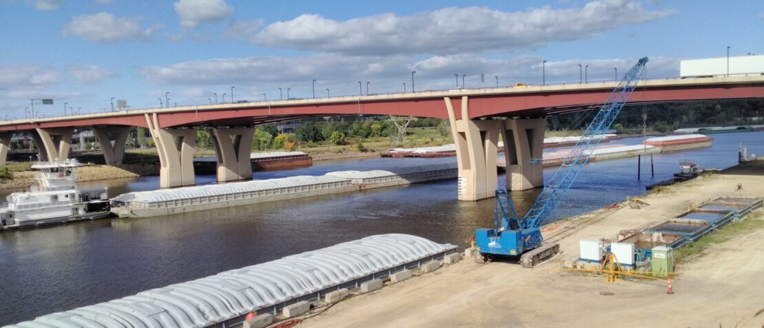 A bridge over water with a blue crane in the foreground.